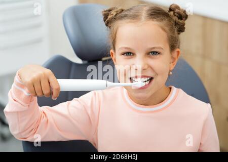 Les dents de la petite fille sont nettoyées avec une brosse à dents sonique électrique. Une brosse à dents moderne qui élimine parfaitement la plaque dentaire Banque D'Images