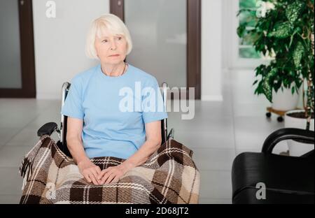 Femme solitaire âgée assise dans un fauteuil roulant dans le couloir de l'hôpital. Personnes handicapées Banque D'Images