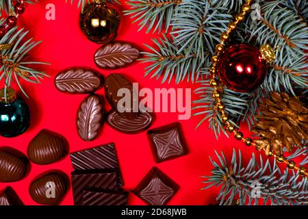 Chocolats sur fond rouge. Décoration et chocolat du nouvel an 2021, bonbons - photo de fête pour la confiserie. Banque D'Images