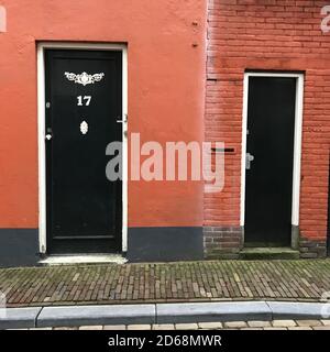 Portes avant vertes dans un mur peint en terre cuite dans la ville avec une chaussée Banque D'Images