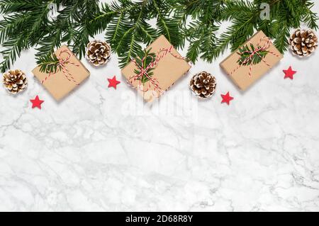Couvre-lit de Noël gratuit en plastique avec boîtes cadeaux faites à la main, branches de conifères, cônes de pin, étoiles en bois sur fond de marbre. Carte de vœux Banque D'Images