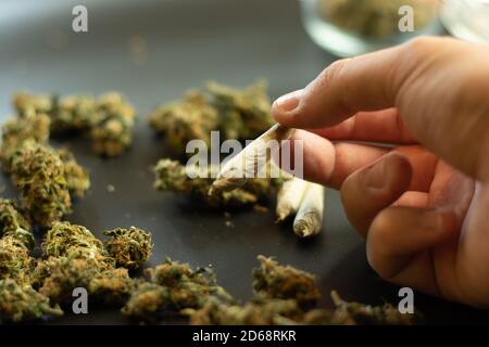 Addiction de drogue concept, homme tenant la marijuana joint dans la main. Copier l'arrière-plan de l'espace avec des bourgeons de cannabis. Programme de tabagisme des mauvaises herbes Banque D'Images