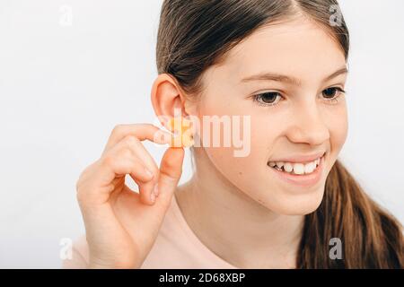 Bouchons d'oreilles individuels pour enfants. Fille tenant un bouchon d'oreille près de l'oreille, gros plan. Banque D'Images