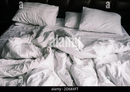 Lit vide non fait avec draps blancs. Draps et oreillers dans l'appartement ou l'hôtel après une nuit de sommeil. Couverture sale et froissés dans l'hôtel Banque D'Images