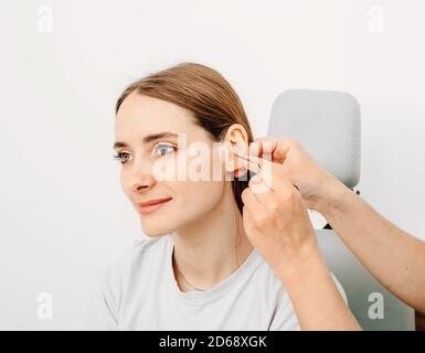 Otolaryngologiste faisant des bouchons d'oreille à partir d'une impression d'oreille de femme individuelle. Bouchons d'oreilles moulés personnellement Banque D'Images