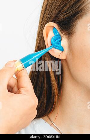 Bouchons d'oreilles moulés personnellement. Processus de fabrication des bouchons d'oreille à partir d'une impression d'oreille d'une femme. Audiologie. Partie de l'ensemble Banque D'Images