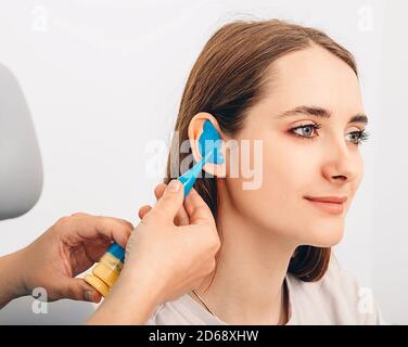 Bouchons d'oreilles moulés personnellement. Processus de fabrication des bouchons d'oreille à partir d'une impression d'oreille d'une femme. Audiologie. Partie de l'ensemble Banque D'Images