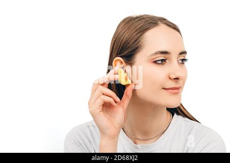 Bouchons d'oreilles individuels pour femmes. Femme tenant le bouchon d'oreille personnalisé près de l'oreille, sur fond blanc Banque D'Images