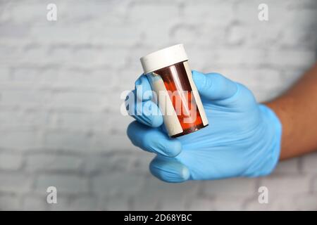homme main dans des gants de protection tenant le contenant de la pilule Banque D'Images