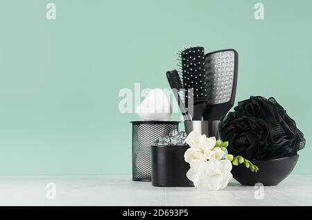 Salle de bains de printemps intérieur avec fleurs de freesia blanc et accessoires de nettoyage de peau, cosmétiques en couleur noire sur la menthe verte menthe mur, bois blanc boa Banque D'Images