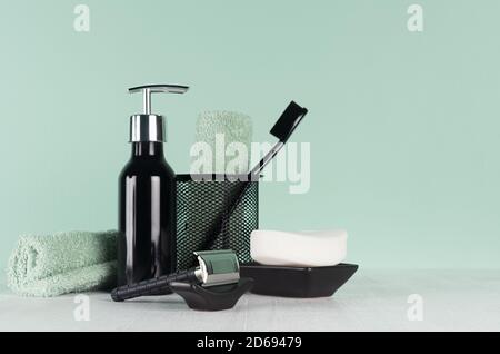 L'intérieur de la salle de bains est à la menthe. Il y a un produit cosmétique pour le bain : rasoir noir, brosse à dents, serviette, distributeur de savon sur une table en bois blanc clair et doux. Banque D'Images