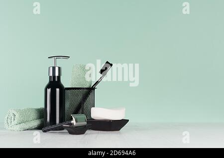 Intérieur frais de salle de bains à la menthe verte menthe couleur - rasoir noir, brosse à dents, savon, serviette, distributeur sur table en bois blanc. Banque D'Images