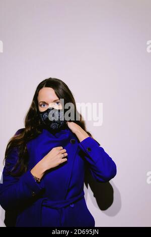 Portrait d'une belle femme avec des yeux bleus portant un filtre de protection N95 tissu masque facial. Modèle attrayant prêt à aller à l'extérieur pendant une pandémie. Banque D'Images