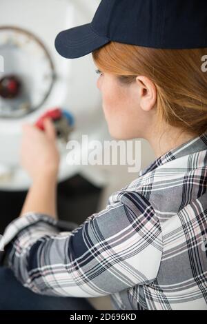 plombier féminin travaillant sur un chauffe-eau Banque D'Images