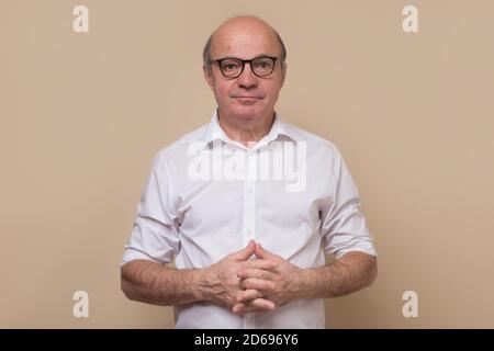 Élégant homme bald senior avec des lunettes souriant confiant à la caméra. Banque D'Images