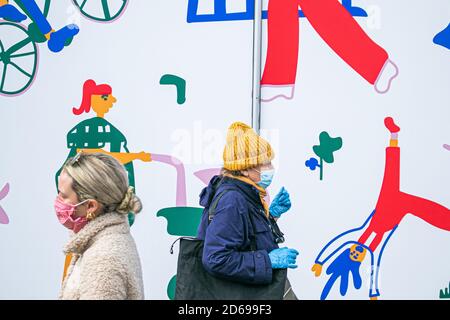 KINGSTON LONDON, ROYAUME-UNI, 15 OCTOBRE 2020. Les acheteurs marchent devant une murale avec des dessins dans le centre-ville de Kingston représentant des gens faisant diverses tâches . Londres va être placée dans un système de verrouillage de niveau 2, car des restrictions plus strictes vont être introduites pour la capitale à partir de samedi 22h suite à un avertissement du maire de Londres Sadiq Khan que les infections à coronavirus se propagent rapidement. Niveau 2, élevé (pas de ménages se mélangeant à l'intérieur, la règle des six s'applique à l'extérieur, les pubs et les restaurants.Credit: amer ghazzal / Alamy Live News Banque D'Images