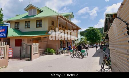 La Digue, Seychelles - 10/01/2018: Une scène animée dans la rue en face d'un petit magasin en centre-ville avec des touristes et des vélos. Banque D'Images