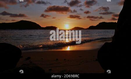 Coucher de soleil majestueux sur la plage tropicale près de Port Launay dans le nord de Mahé, Seychelles avec soleil de couleur orange entre les silhouettes de deux îles. Banque D'Images