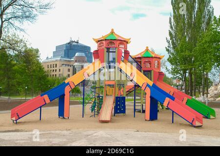 Terrain de jeu coloré pour enfants sur une cour de sable à proximité de beaux bâtiments. Banque D'Images