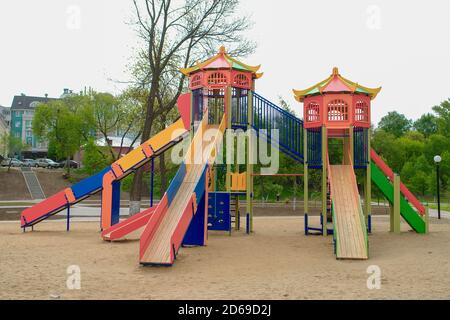 Terrain de jeu coloré pour enfants sur une cour de sable à proximité de beaux bâtiments. Banque D'Images