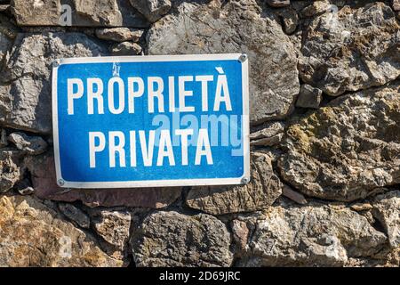 Proprieta Privata, bleu et blanc signe de propriété privée en langue italienne suspendu sur un mur en pierre. Ligurie, Italie, Europe Banque D'Images