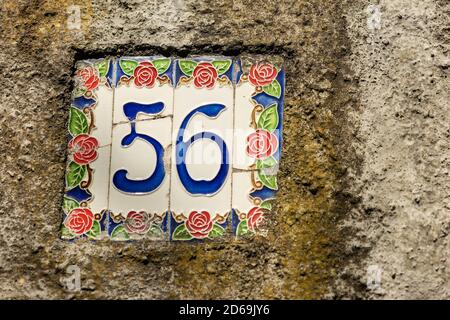 Gros plan de la maison numéro 56 (cinquante-six) sur le mur dans un petit village. Ligurie, Italie, Europe. Banque D'Images