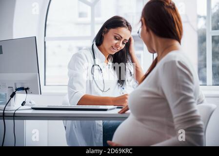 La femme enceinte a la consultation avec obstétricien à l'intérieur Banque D'Images