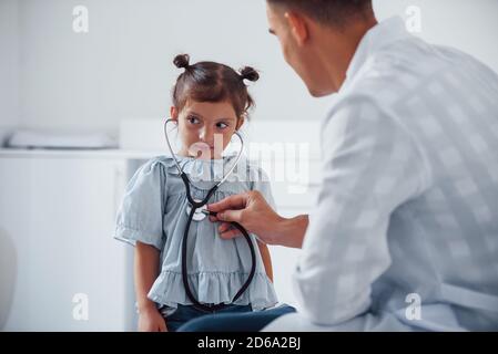 Jeune pédiatre travaille avec une petite femme visiteur dans la clinique Banque D'Images