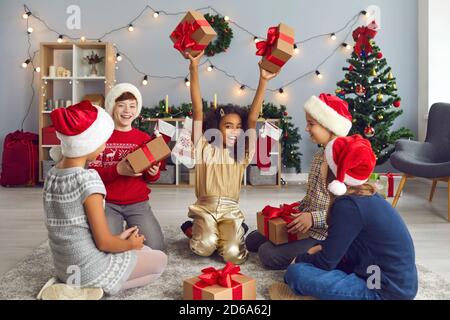 Groupe d'enfants heureux, excités, multiraciaux, amis ou frères et sœurs, échanger des cadeaux à la maison Banque D'Images