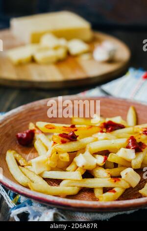 Frites de la poutine sur la surface noire. Plat canadien avec pommes de terre, fromage et sauce Banque D'Images