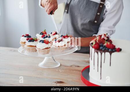 Vue rapprochée de la femme qui fait des tranches de l' biscuits à l'aide d'un couteau dans la cuisine avec tarte la table Banque D'Images