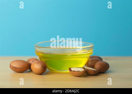 Fond d'huile d'argan. Noix d'argan et huile sur une table en bois sur fond bleu vide. Copier l'espace Banque D'Images