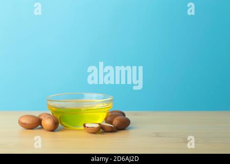 Fond d'huile d'argan. Noix d'argan et huile sur une table en bois sur fond bleu vide. Copier l'espace Banque D'Images