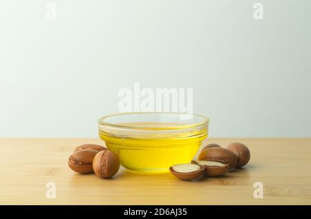 Fond d'huile d'argan. Noix d'argan et huile sur une table en bois sur fond blanc vide. Copier l'espace Banque D'Images