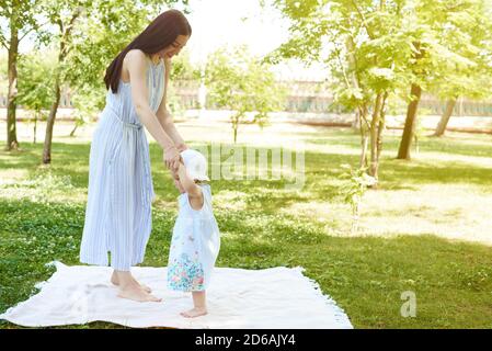 Une mère heureuse et une petite fille marchent dans le parc. Mère et fille sont sur la couverture dans le parc. Banque D'Images