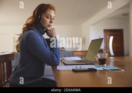 Femme qui porte un micro-casque/une oreillette travaillant à la maison Banque D'Images