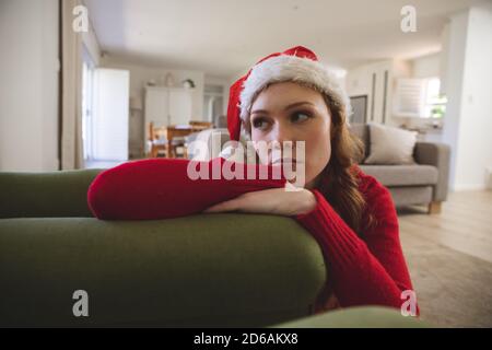 Triste femme portant le chapeau de Santa, penchée sur le canapé à accueil Banque D'Images