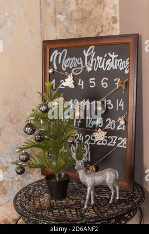 Compte à rebours jusqu'au calendrier de l'Avent de Noël. Décoration de Noël avec petit sapin, décoration, boules, bougies, renne et tableau noir sur fond gris Banque D'Images