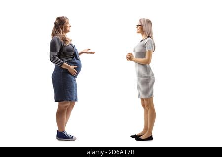 Photo de profil pleine longueur d'une femme enceinte et d'un femme blonde ayant une conversation isolée sur fond blanc Banque D'Images