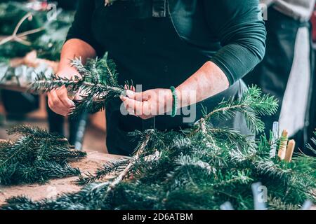 brindilles de pin vert, feuilles d'eucalyptus, ciseaux, composants de base ronds en paille pour l'artisanat dyi avec les mains en action Banque D'Images