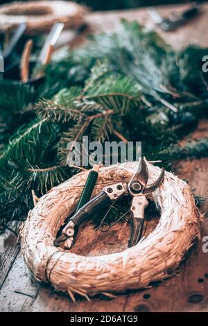 base ronde en paille, ciseaux et branches vertes sur table en bois Banque D'Images