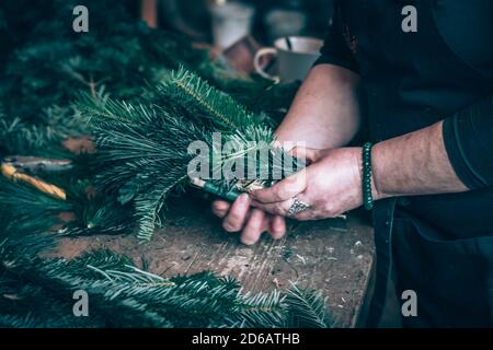 base ronde en paille, ciseaux et branches vertes dans les mains humaines en action Banque D'Images