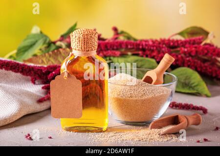 Huile d'Amaranth dans une bouteille et gris d'amaranth dans un bol en verre avec branche d'amaranth en fleur, gros plan avec foyer sélectif Banque D'Images