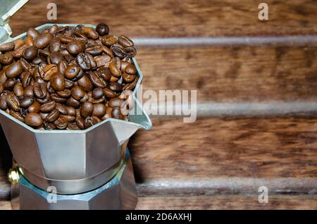 Café dans une marmite avec grains de café et café moulu sur fond sombre et flou. Banque D'Images