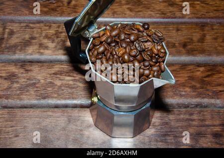 Café dans une marmite avec grains de café et café moulu sur fond sombre et flou. Banque D'Images