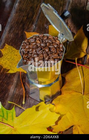 Café dans une marmite avec grains de café et café moulu sur fond sombre et flou. Banque D'Images