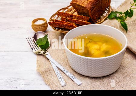 Soupe de truite avec légumes à couper et pain grillé. Soupe traditionnelle de poisson chaud pour un style de vie sain. Fond en bois blanc, gros plan Banque D'Images