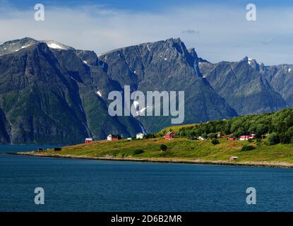 Vue sur les Alpes de Lyngen avec UN petit village Dans le Foreground à Lyngenfjord lors D'UNE Sunny Summer Day Avec UN ciel bleu clair et quelques nuages Banque D'Images