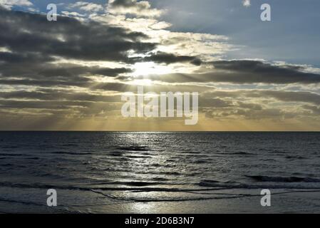 Coucher de soleil sur la mer d'Irlande, tel qu'illustré sur la promenade de Blackpool dans le Lancashire, Angleterre. Les rayons du soleil traversent la couverture nuageuse. Banque D'Images