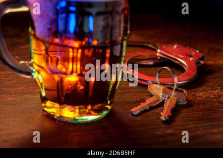 Chope de bière mousseuse avec des menottes et clés symbolisant l'alcool au volant l'arrestation Banque D'Images